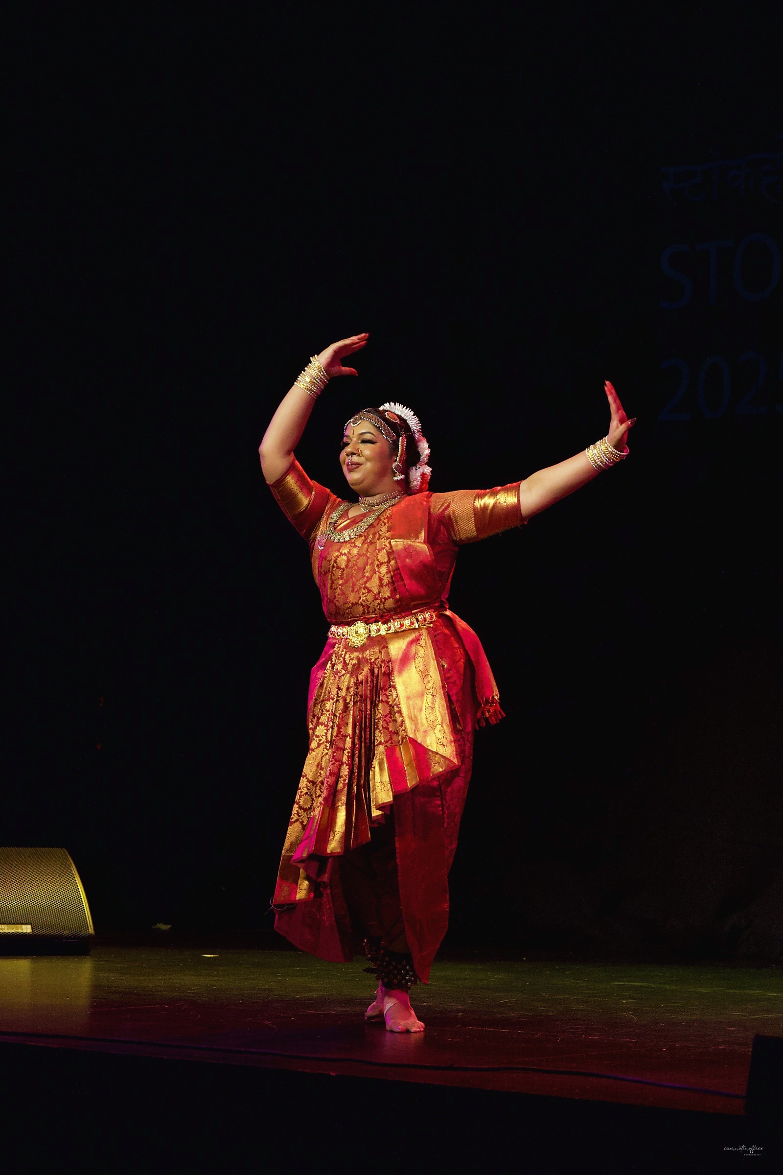Classical Indian dancer with arms raised overhead on stage