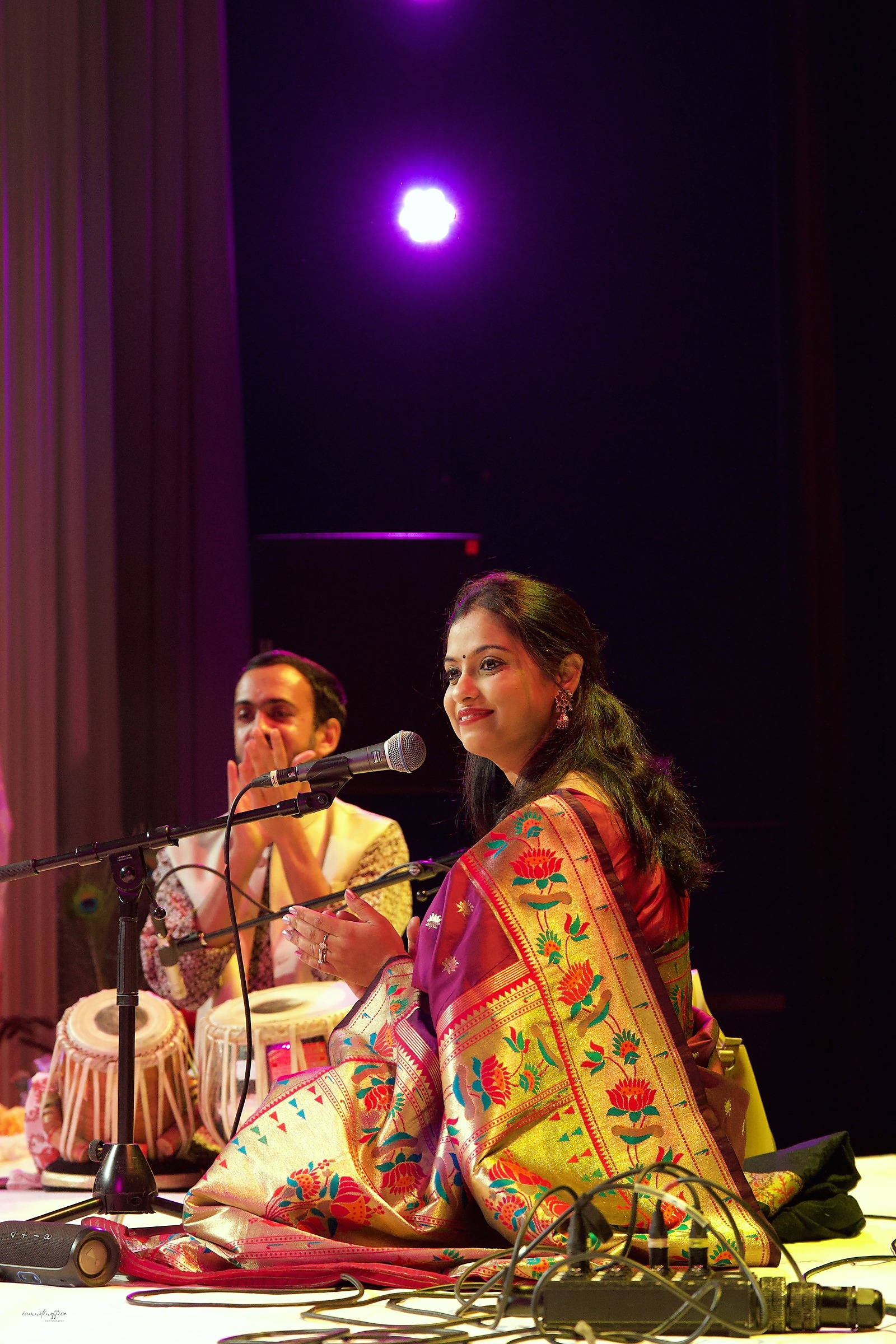 Two musicians performing together, vocalist and tabla player, on stage