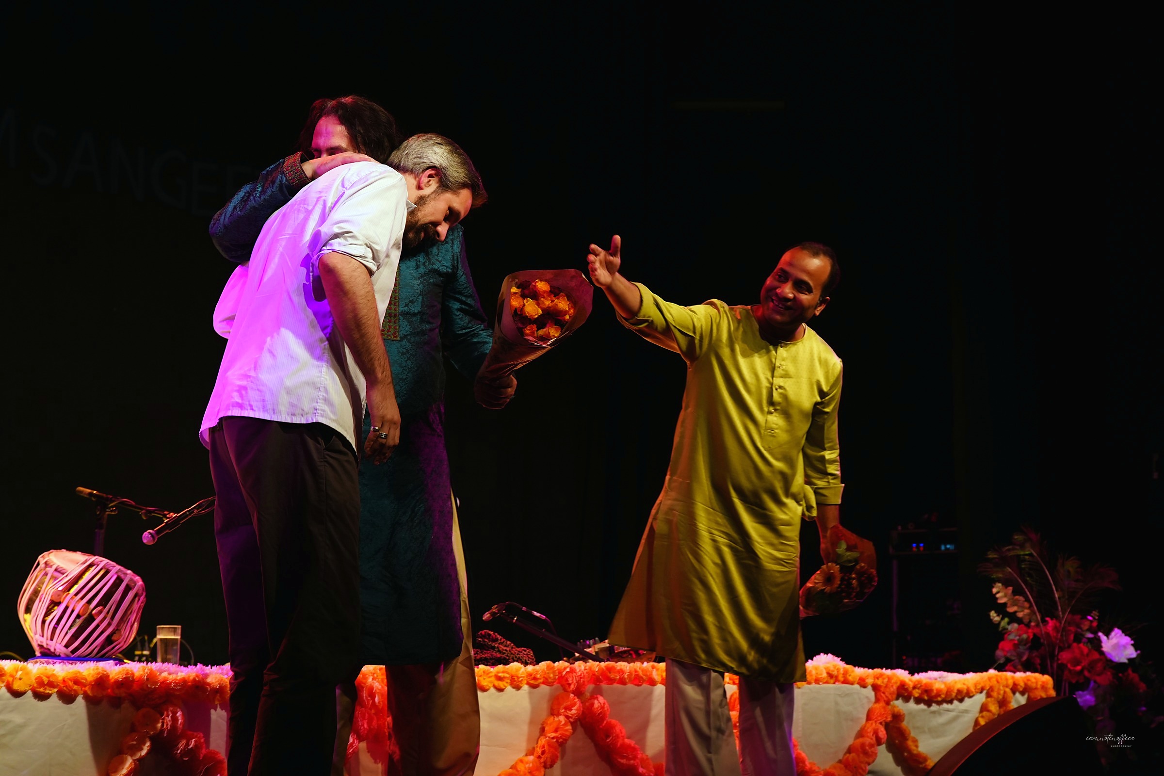 Group of performers embracing with flowers after a performance