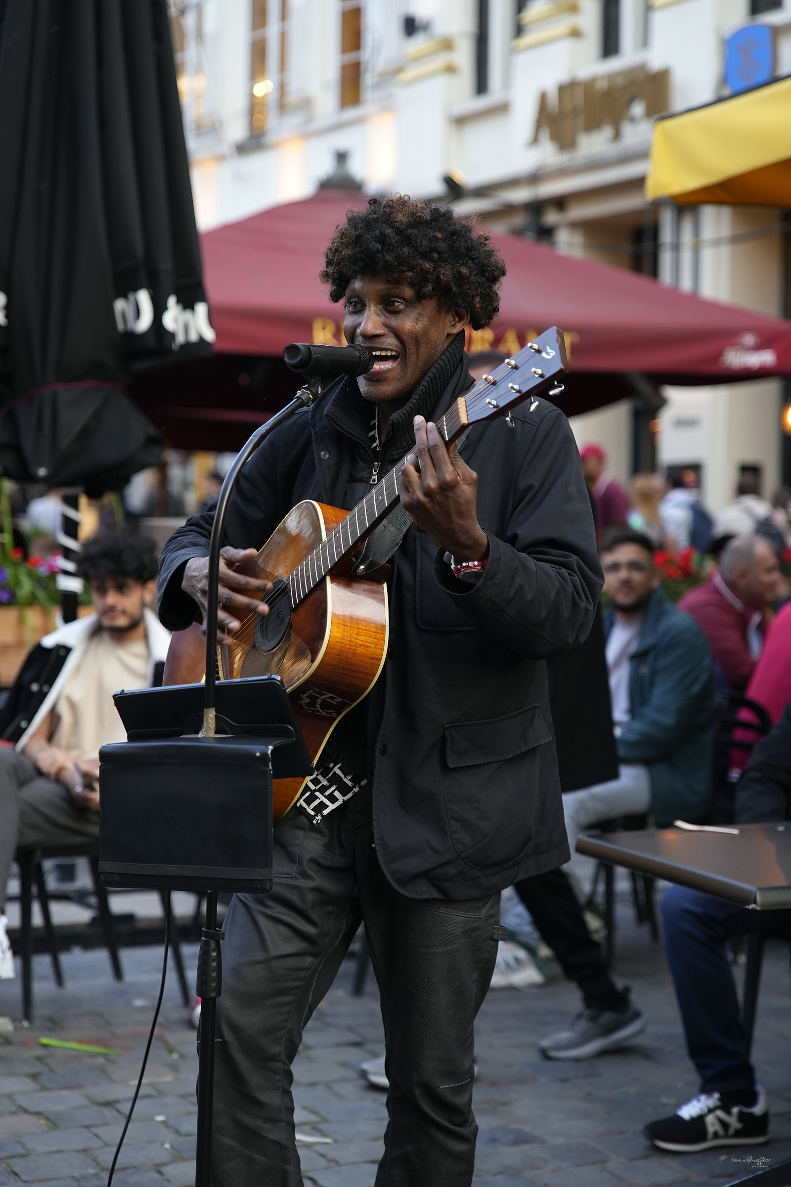 Street musician performing with an acoustic guitar in a busy plaza