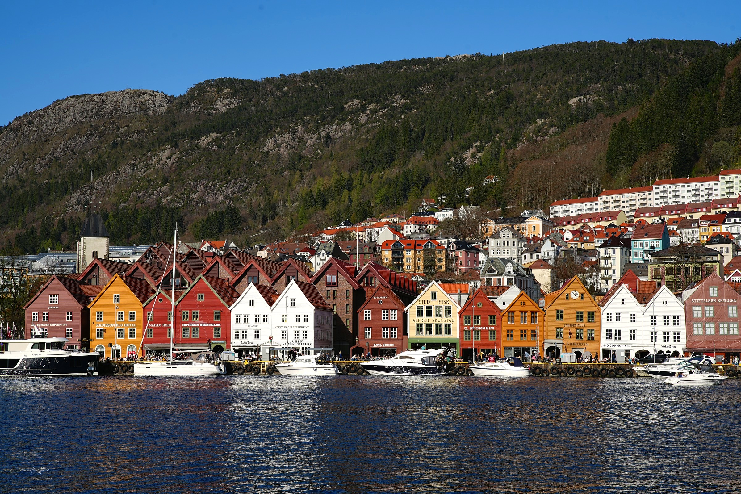 The colorful wooden waterfront houses of Bryggen in Bergen, Norway, with boats moored along the harbor