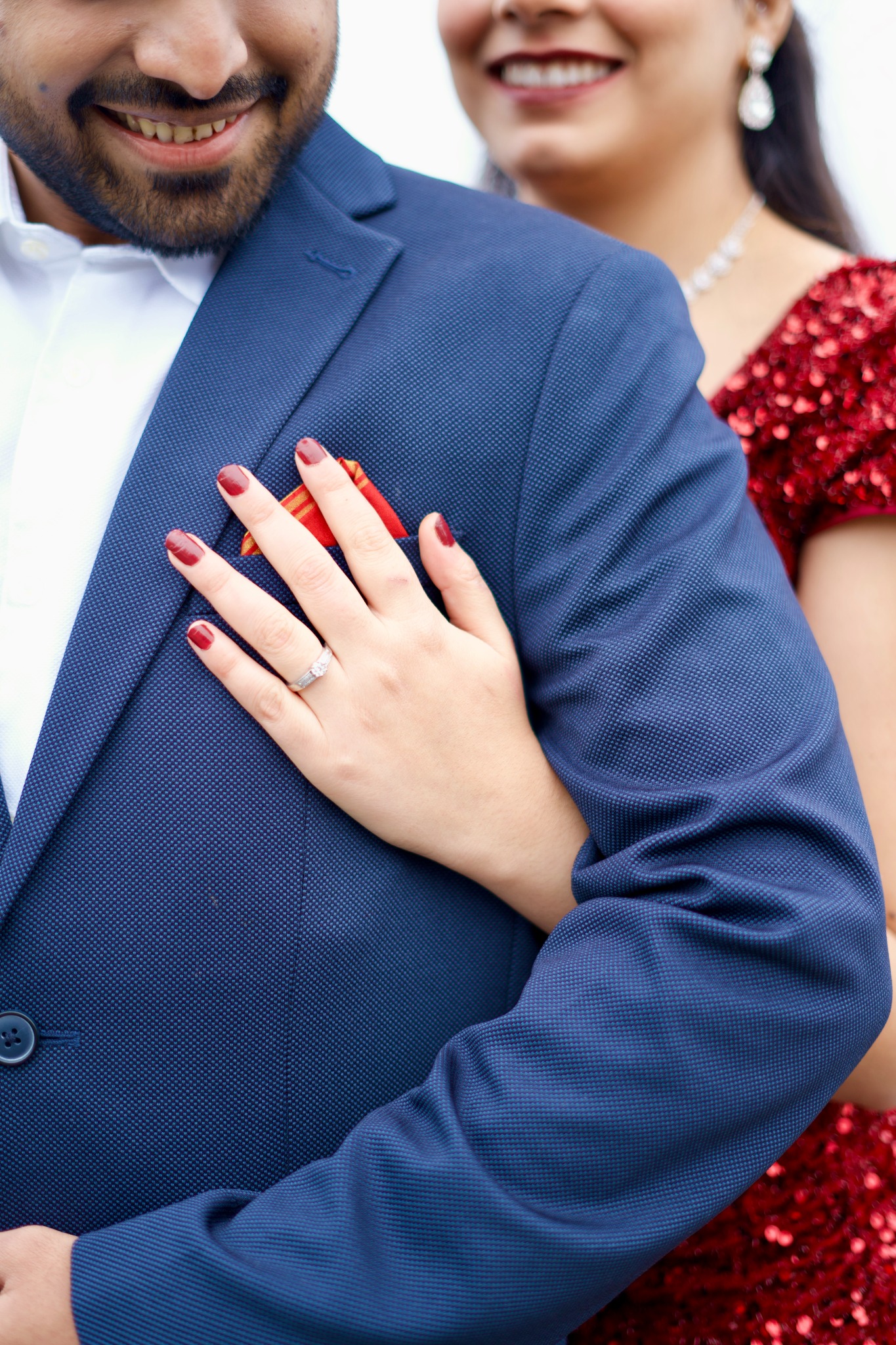 Close-up of couple with engagement ring resting on groom's jacket