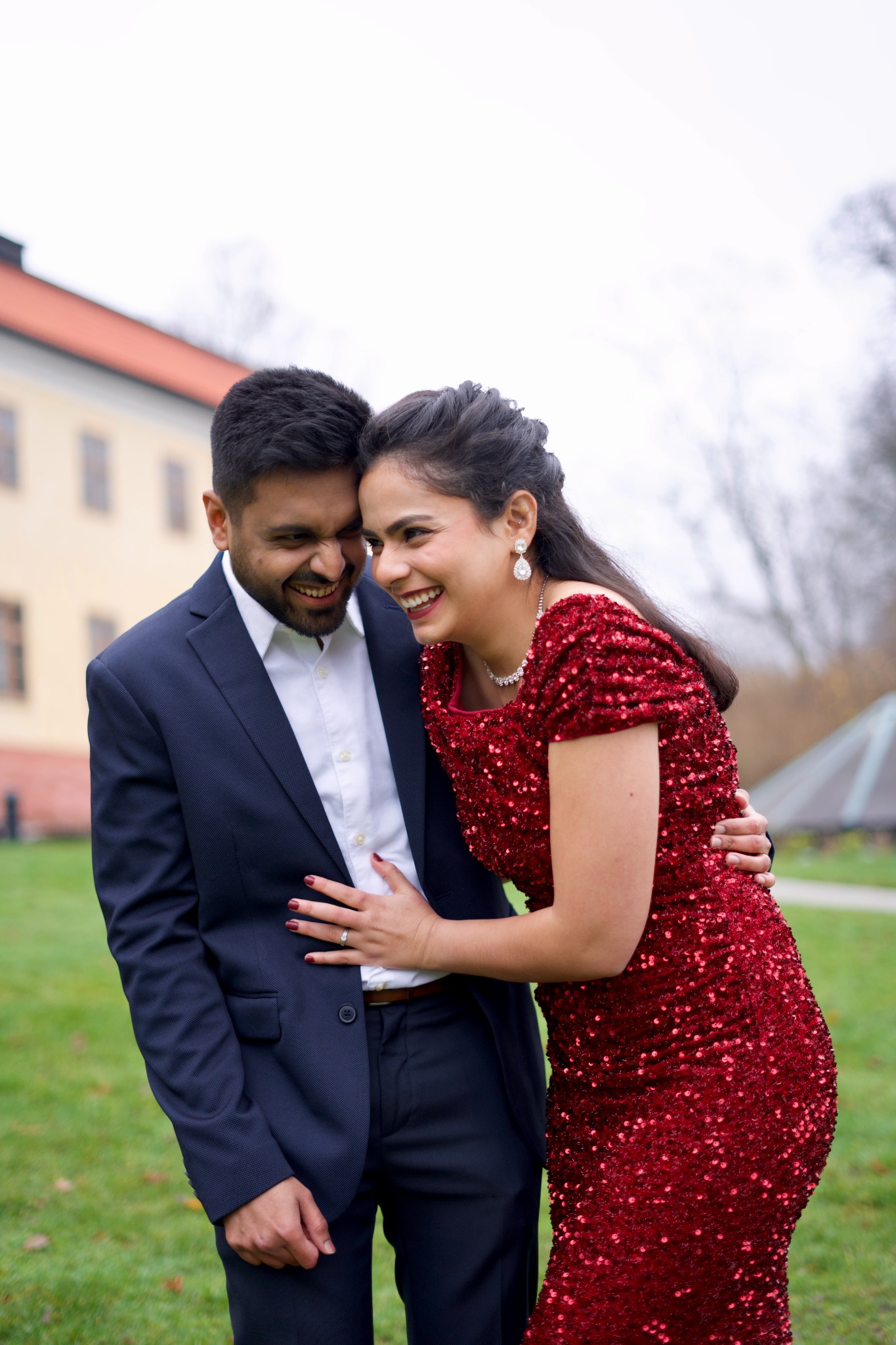 Couple laughing together outdoors in a red sequined gown and blue suit