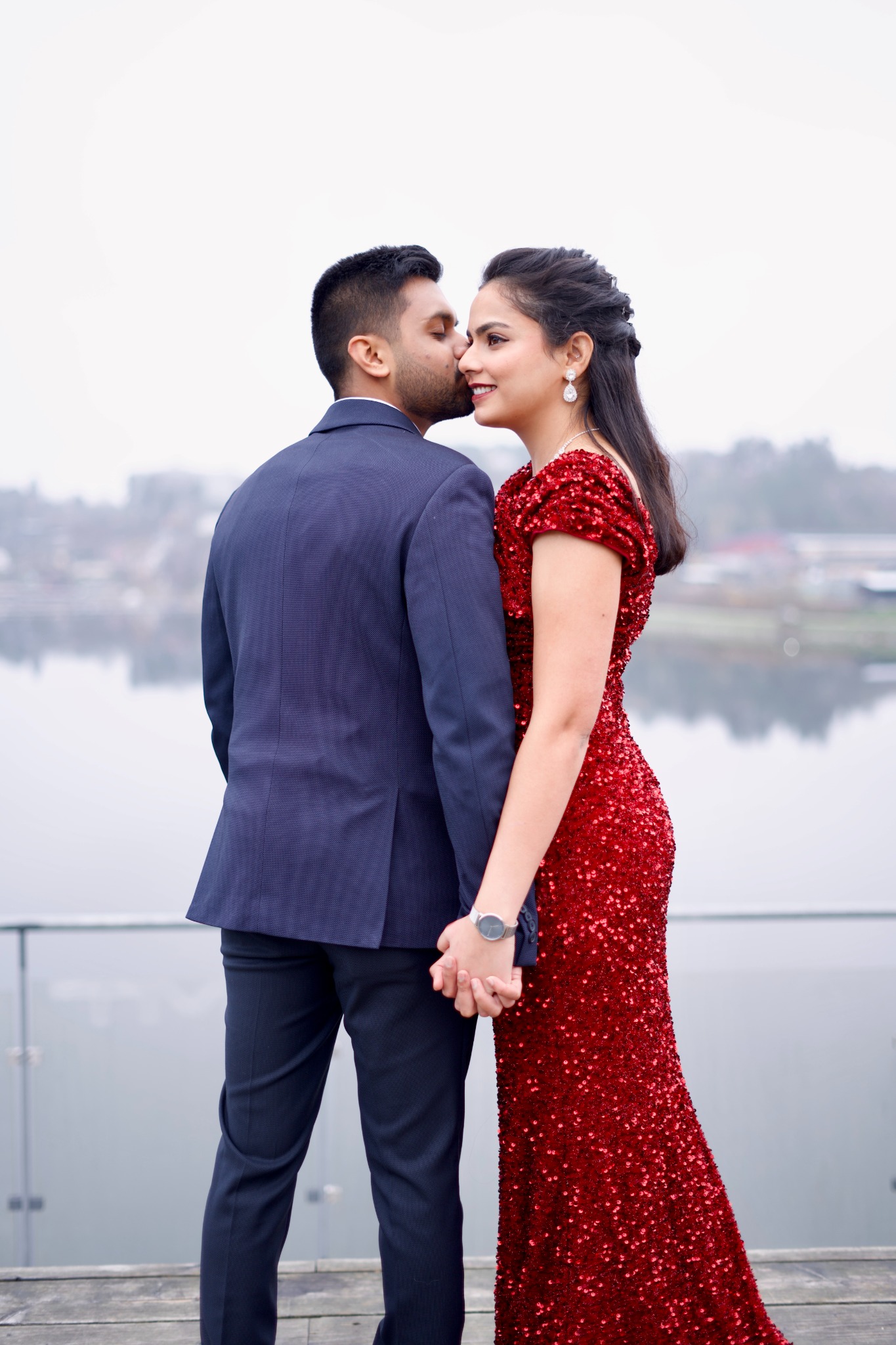 Couple holding hands and smiling under warm chandelier light indoors